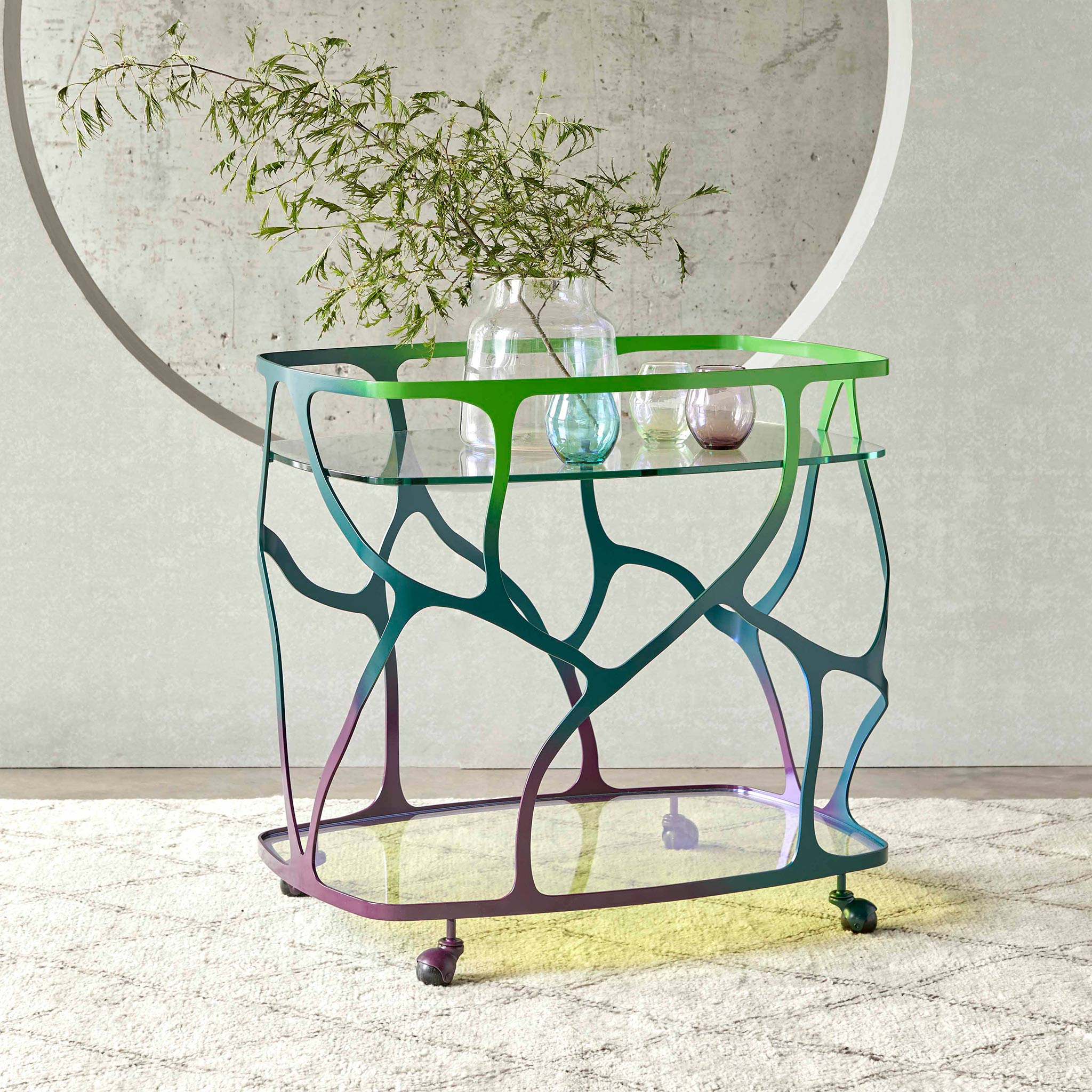 Finished in a "Mariposa" verde finish with a dichroic glass top and shelf