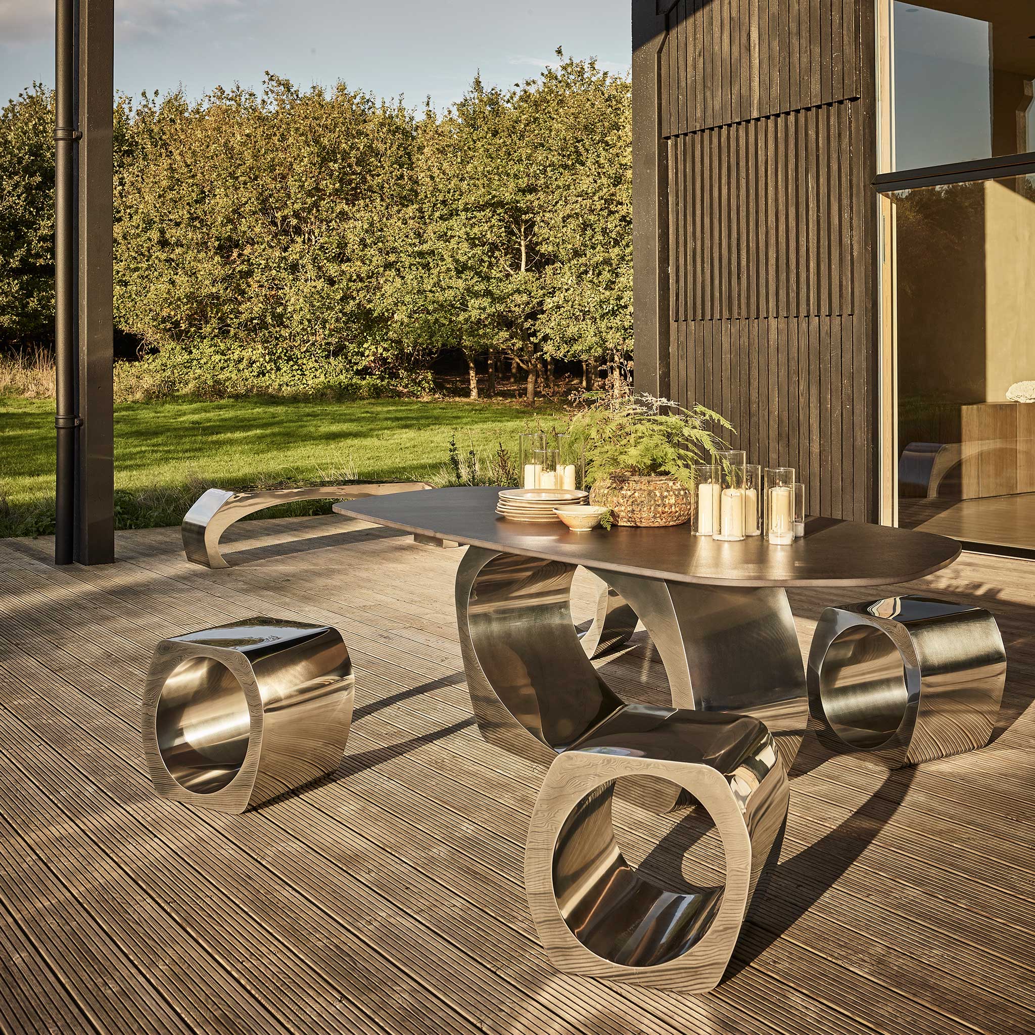 Skye dining table with Dekton top and Skye stools in polished stainless steel, for outdoors
